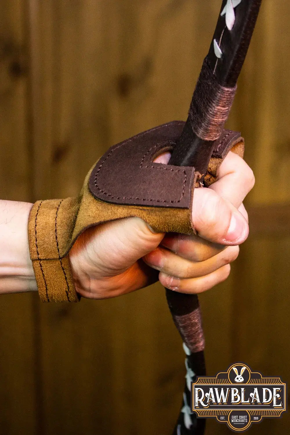 Archery Glove Oren worn while gripping a bow, showcasing quality split leather and adjustable design.