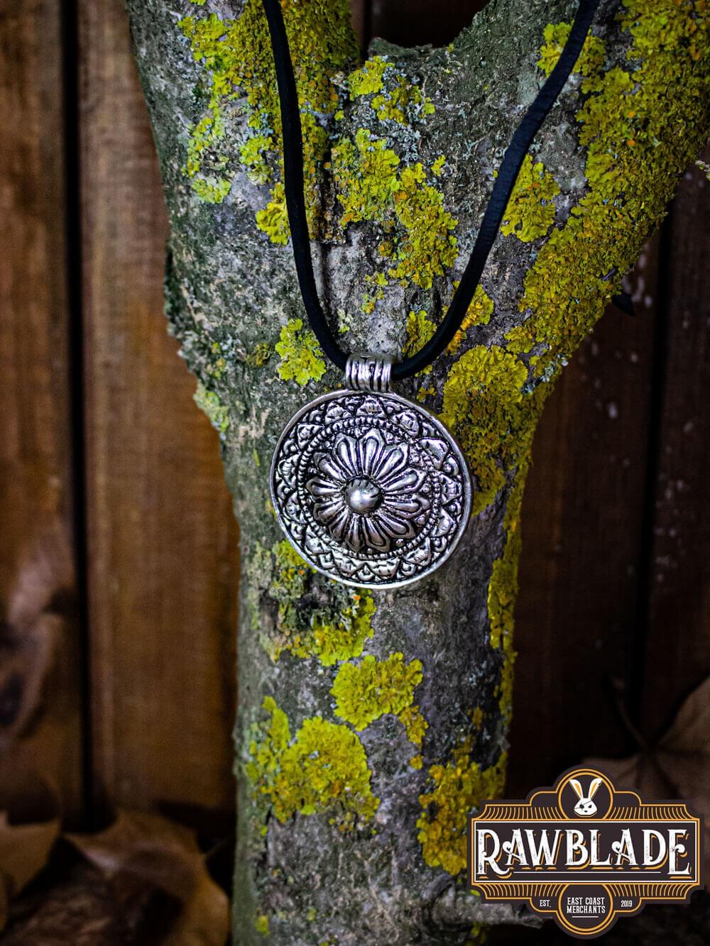 Capadocian Amulet pendant hanging on a tree, featuring a circular design with floral motifs and intricate trimmings.