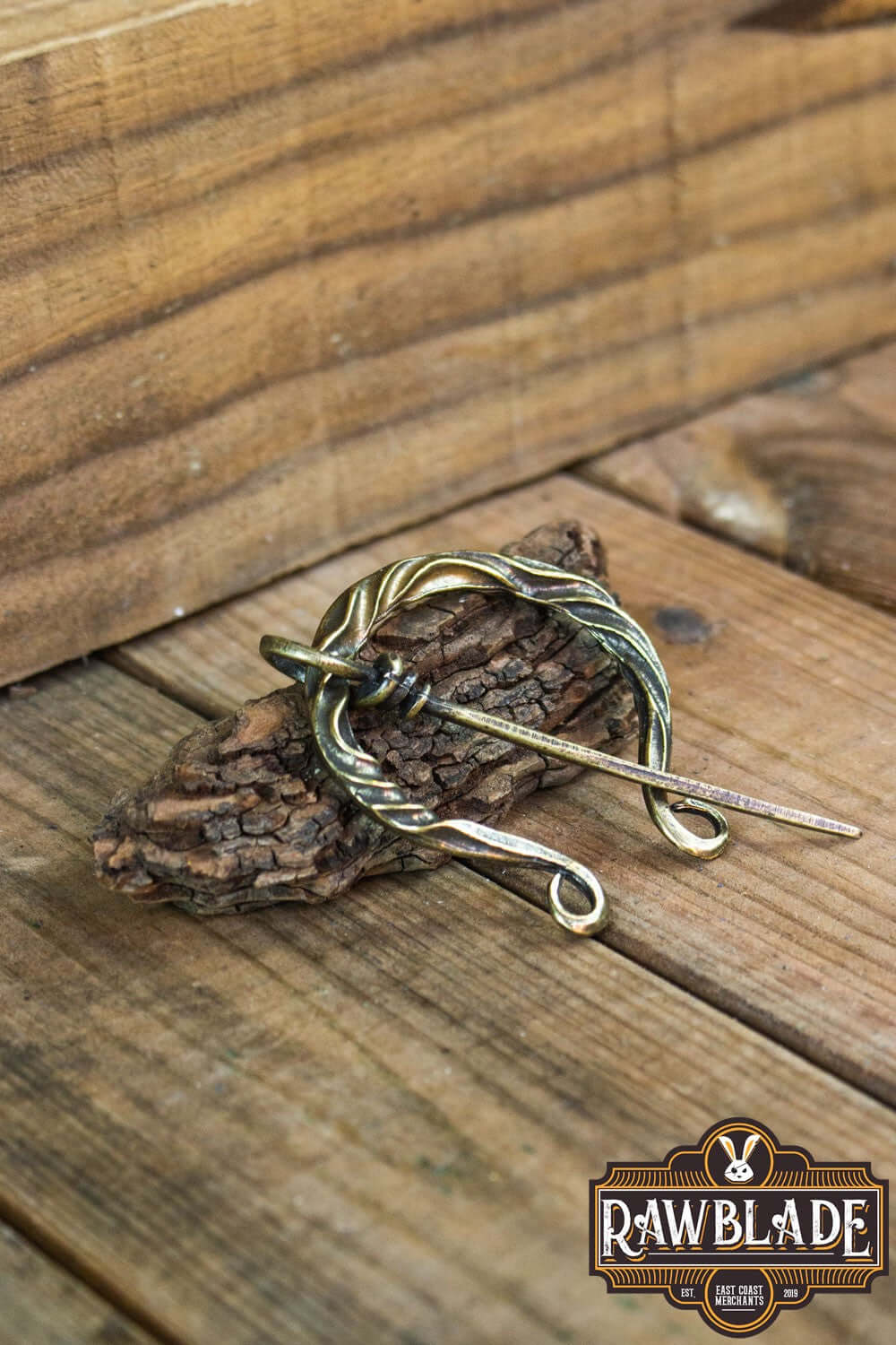 Braided Fibula resting on wood, perfect for medieval costumes and historical reenactments.