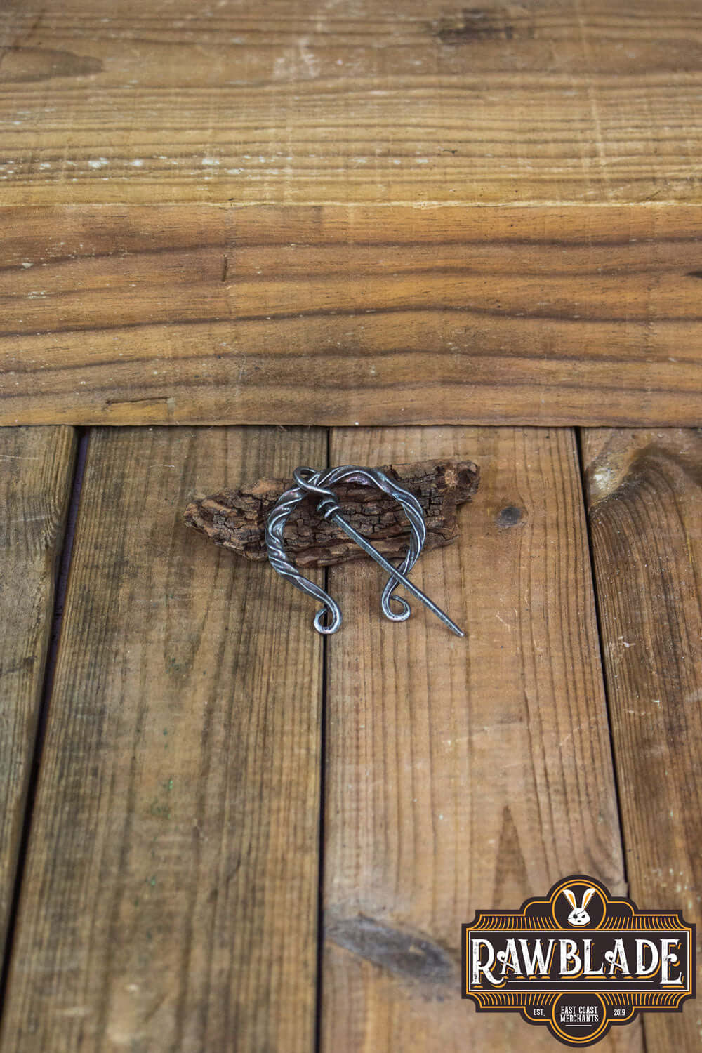 Braided Fibula displayed on wooden surface, perfect for medieval costumes and historical reenactments.