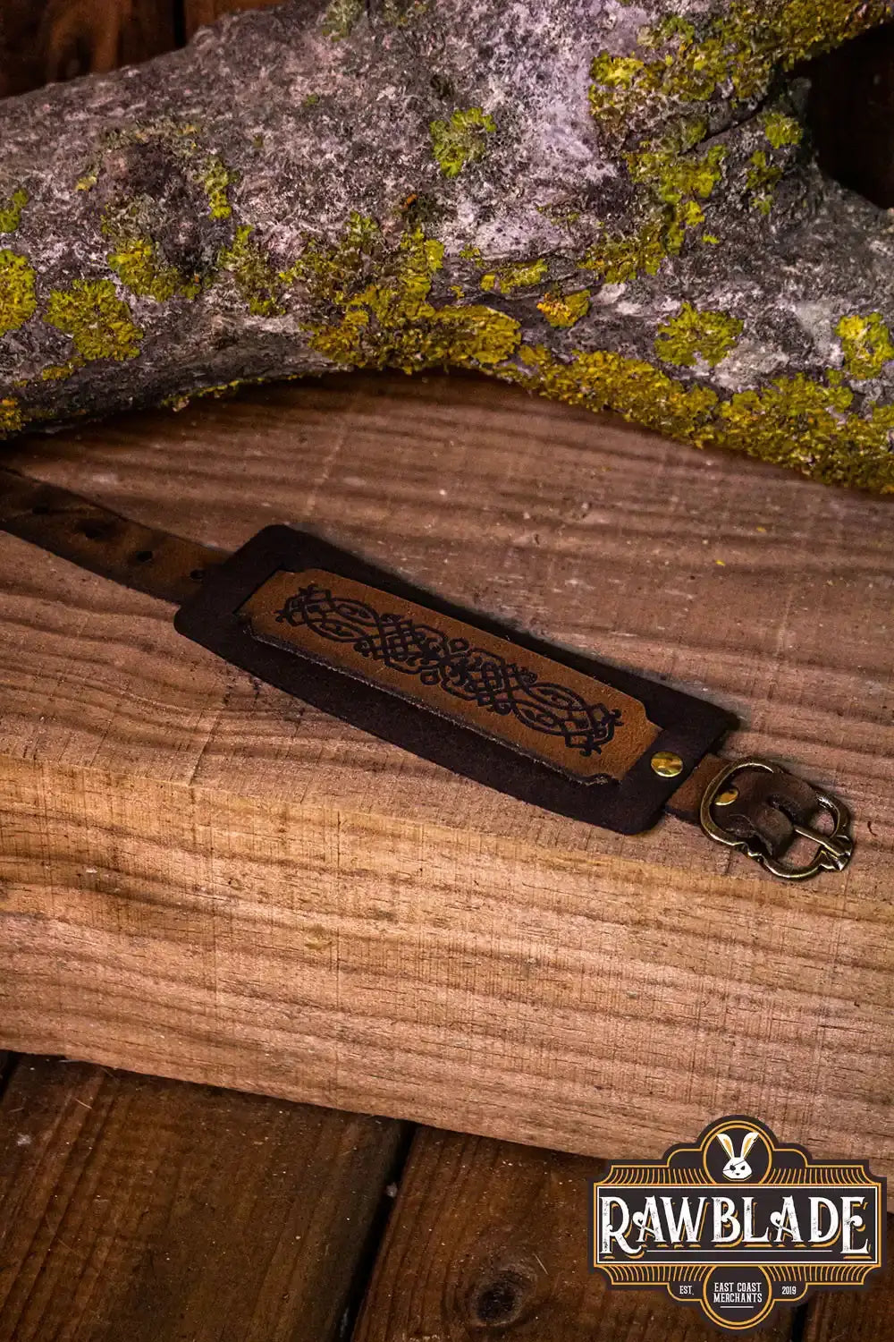 Beleriand Leather Bracelet displayed on wooden surface, showcasing elegant filigree design and adjustable golden buckle.