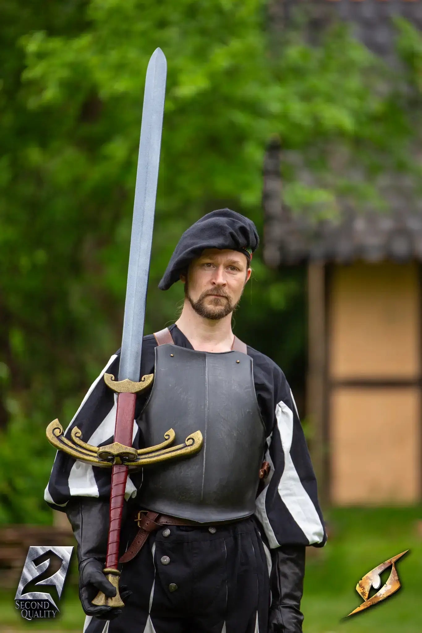 A reenactor holding a 2nd Quality – Landsknecht Greatsword, showcasing Renaissance-style armor outdoors.