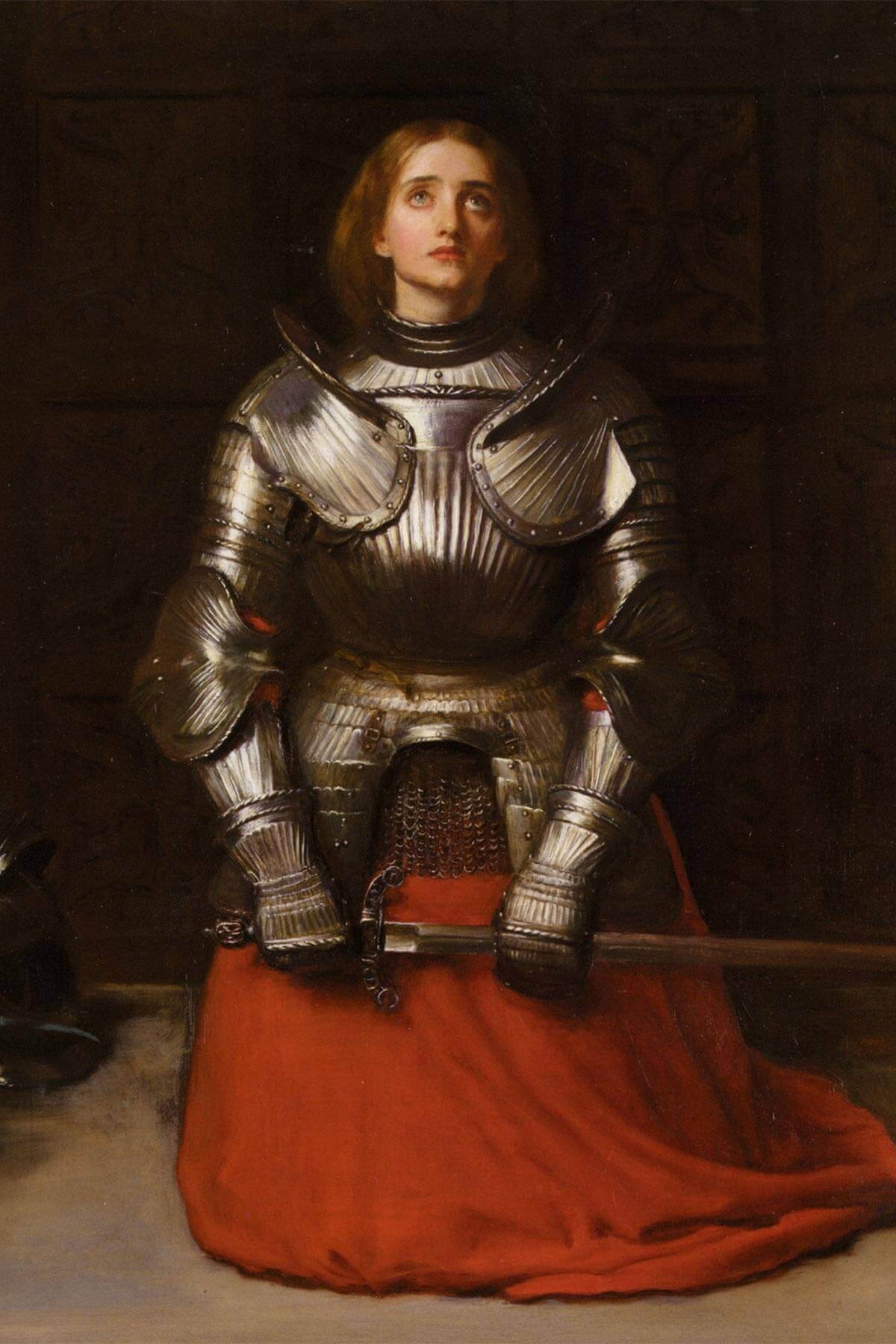 A young knight in shining armor, seated with a sword, wearing a red cape and displaying a solemn expression.