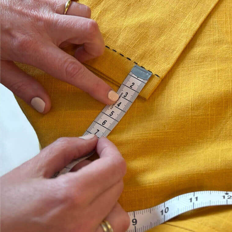 Person measuring the edge of a yellow piece of clothing