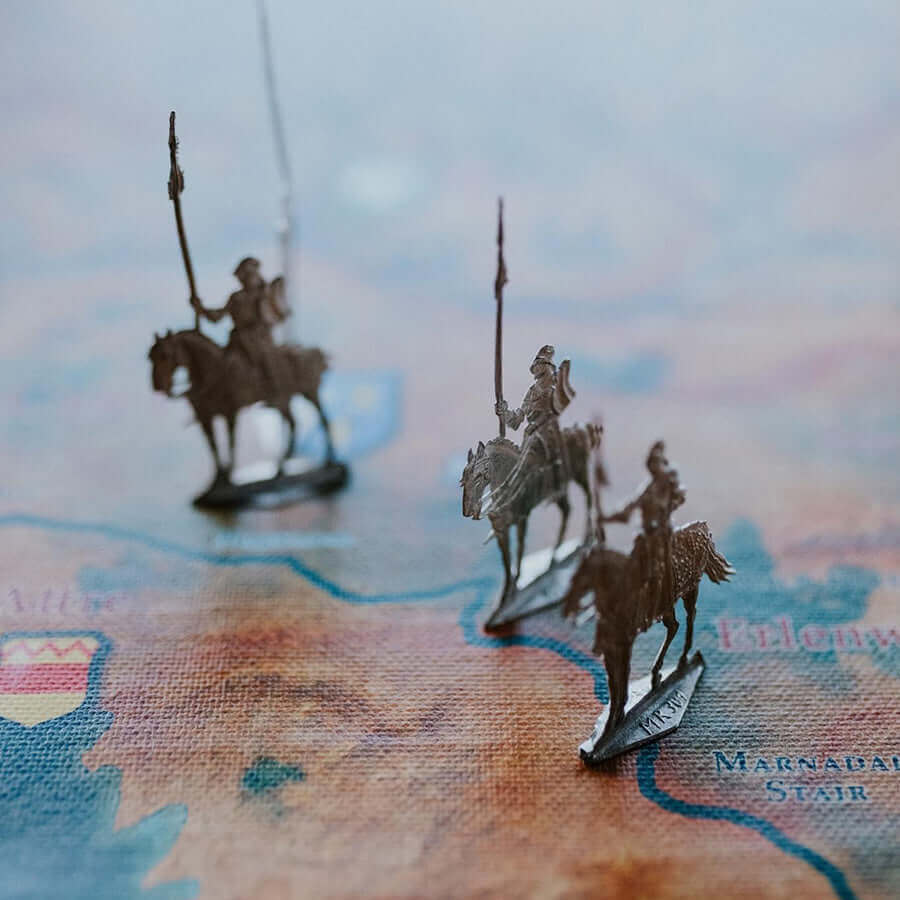 Miniature knights on horseback positioned on a colorful historical map, representing strategy and exploration.
