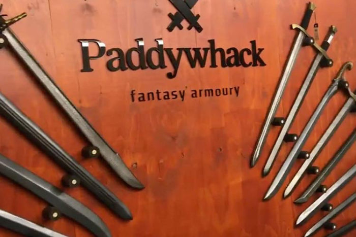 Display of fantasy swords at Paddywhack, showcasing unique craftsmanship on a wooden wall.