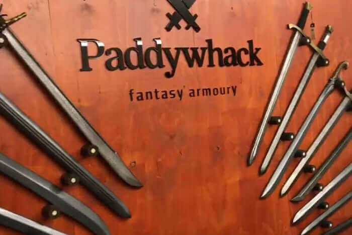 Display of fantasy swords at Paddywhack, showcasing unique craftsmanship on a wooden wall.