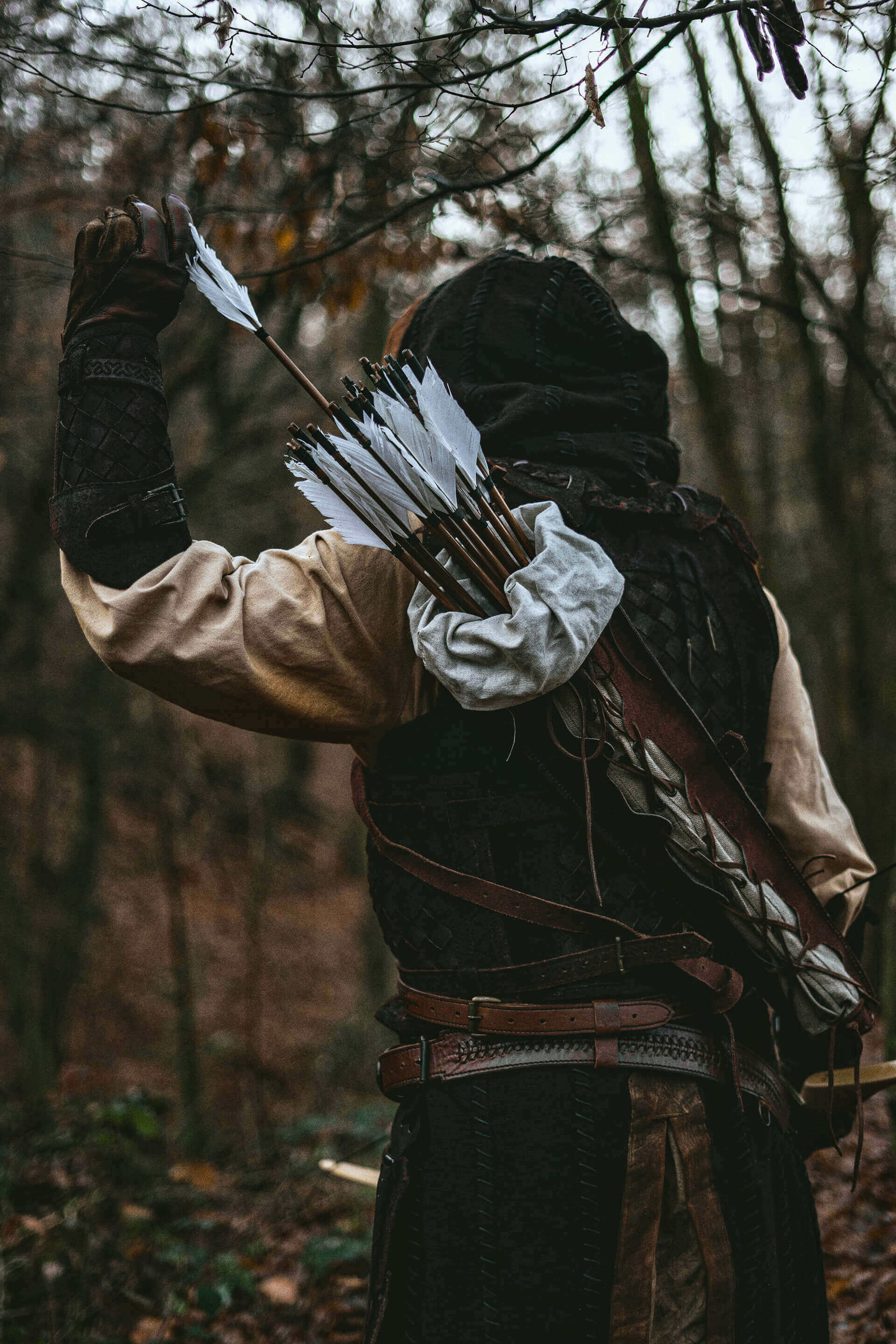 Archer holding a bow with a quiver of arrows, set in a dense forest background.