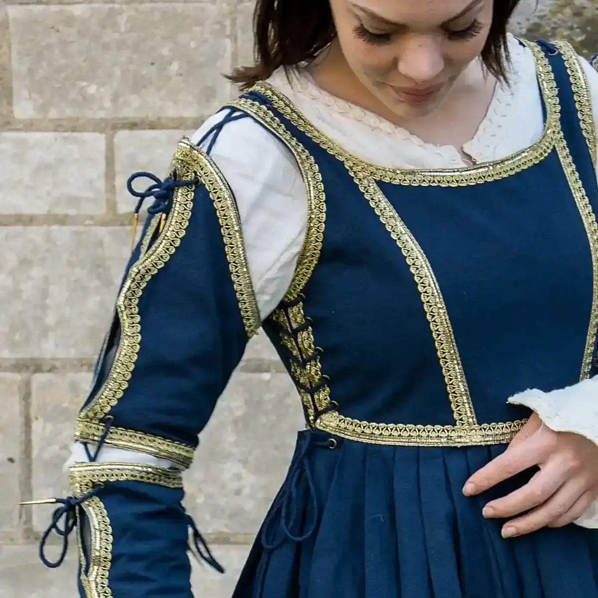 Woman wearing a historical blue dress with gold trim, showcasing detailed craftsmanship and elegant design.