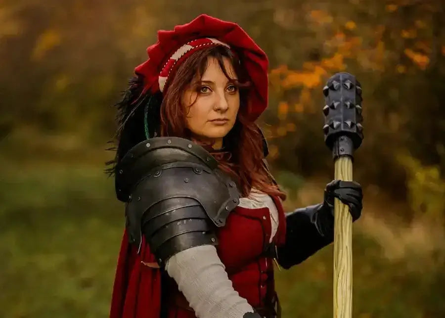 LARP participant in red clothing and shoulder armour holding a foam mace in an outdoor setting.
