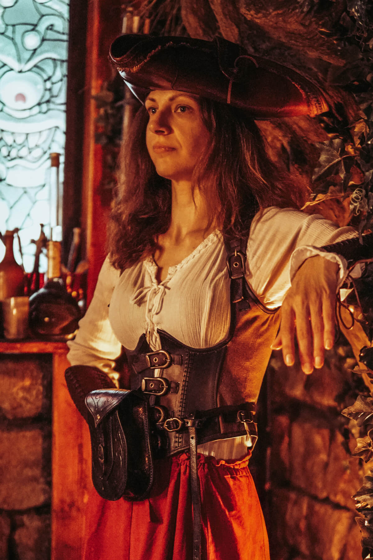 Person in a pirate costume standing in a rustic interior setting.