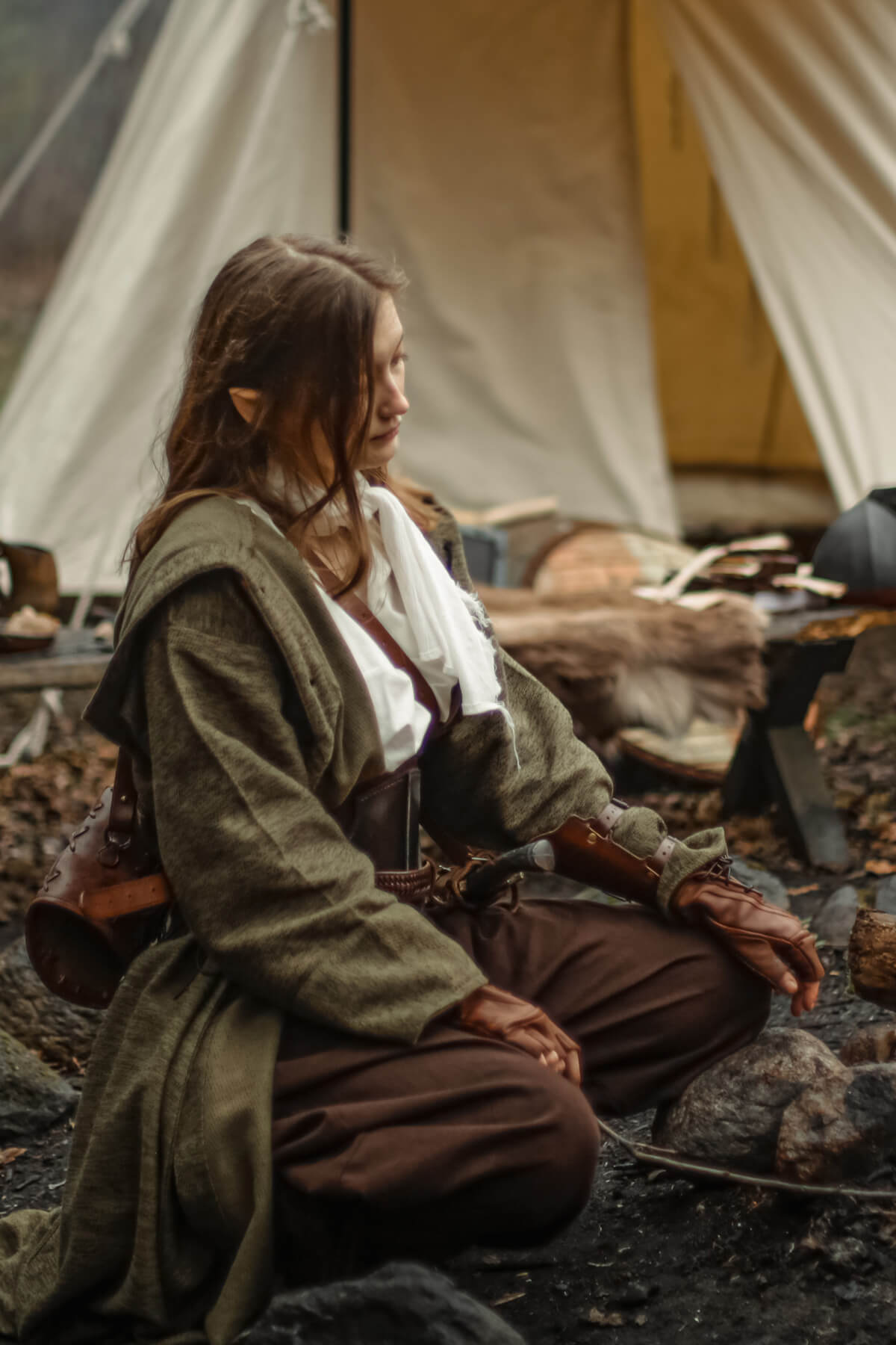 Person in fantasy costume sitting near a tent with camping gear.