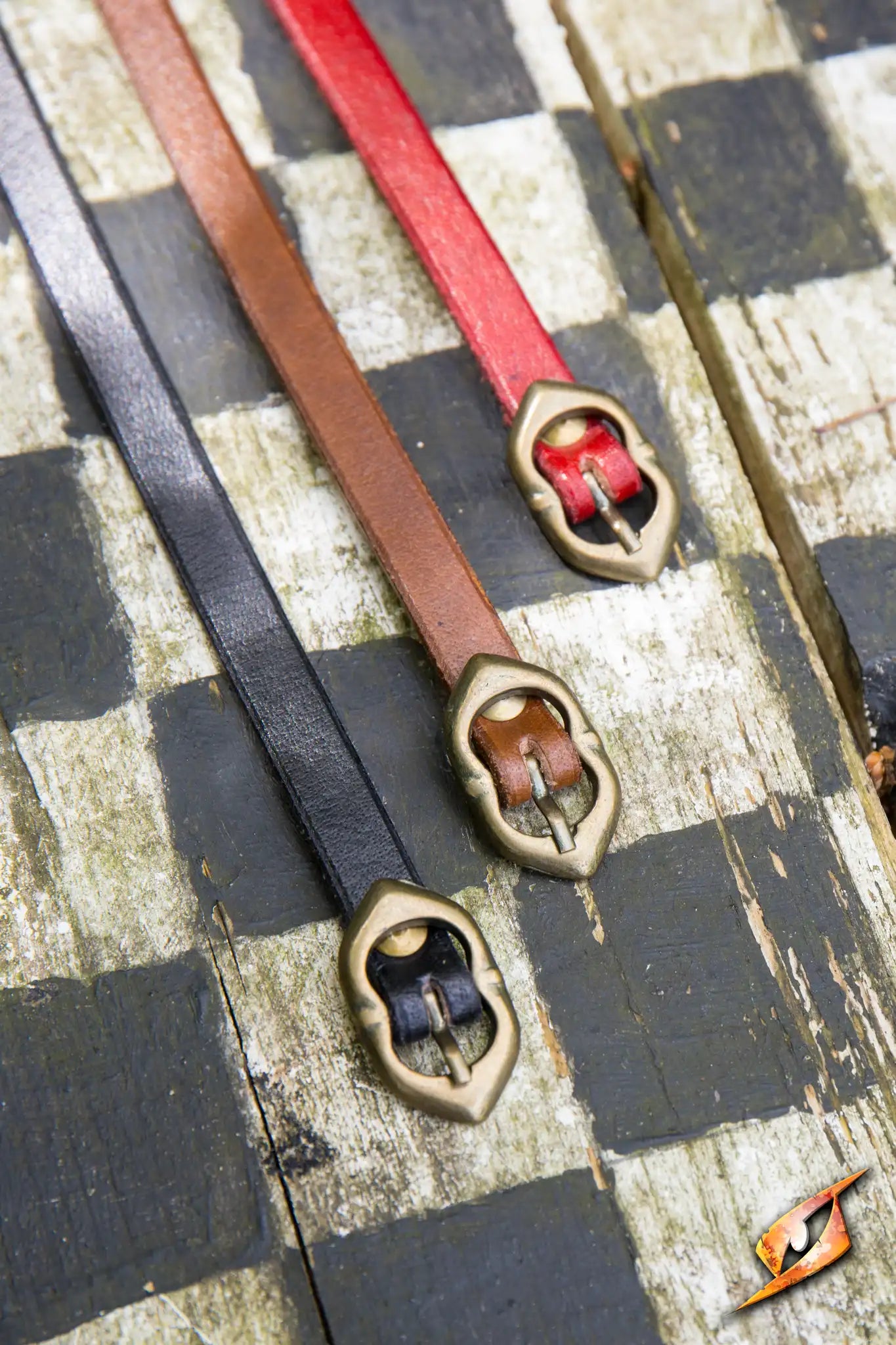 Three medieval belts in black, brown, and red on a wooden surface, showcasing the classic design of Belts.