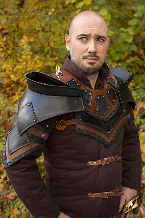 A man wearing a sturdy leather neck and shoulders armor, looking ready for battle in an outdoor setting.