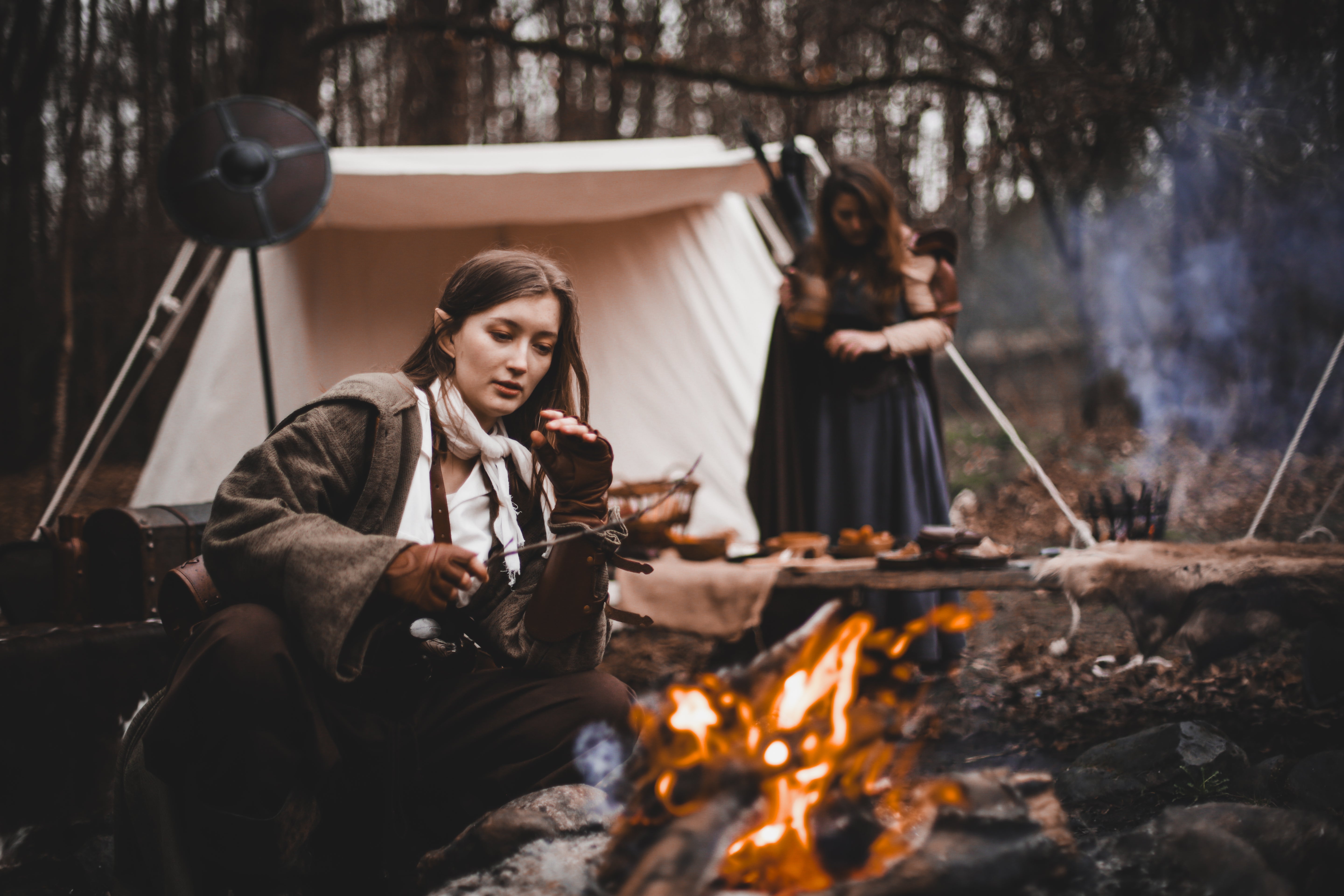 Adventure & Camp Gear: Adventurers preparing food by a campfire in a forest setting.