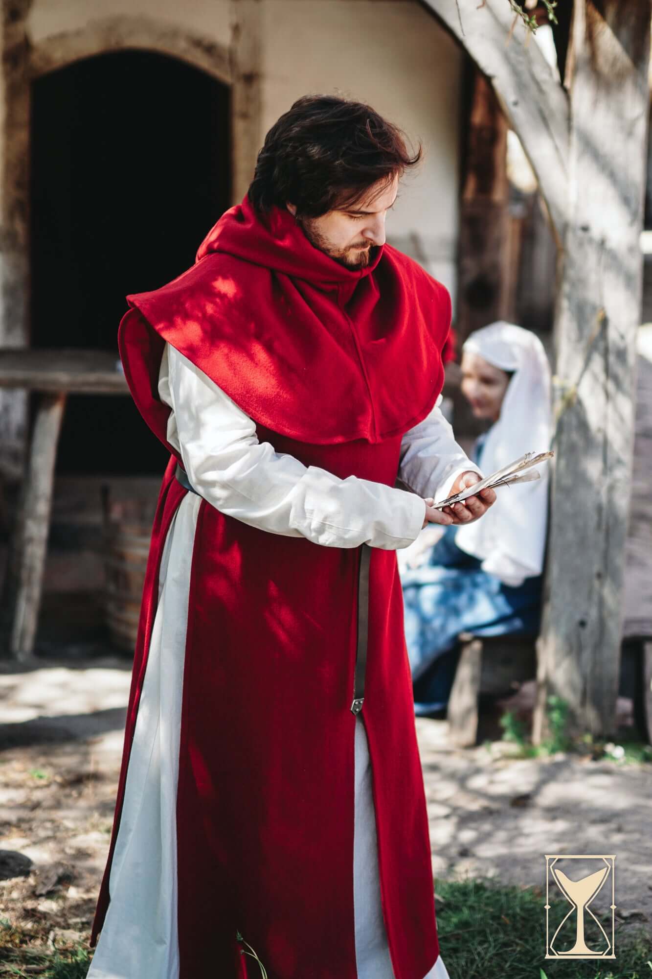 Man wearing Simple Liripipe Hood - Brushed Wool, reading in a medieval setting.