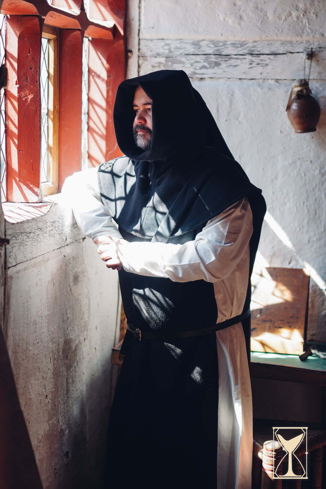 Simple Liripipe Hood - Brushed Wool worn in a medieval setting by a man leaning against a window.
