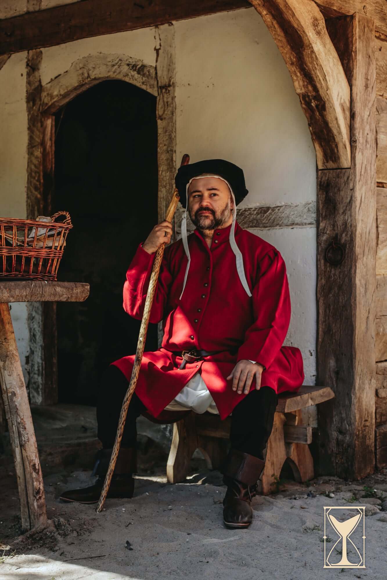 Surcoat Lorenzo worn by a man seated with a walking stick, showcasing 14th century style and design.