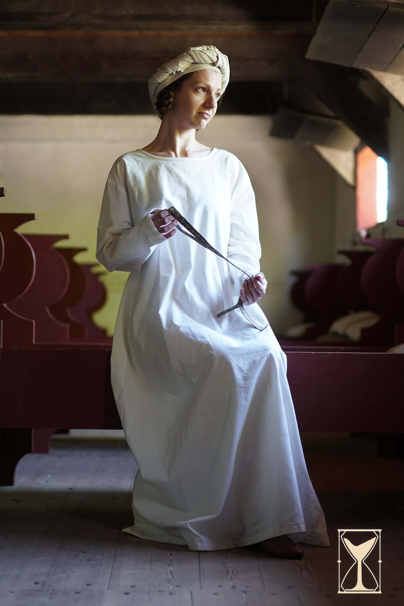 Woman in white dress wearing Rectangular Veil and Fillet - Cotton/Linen Blend, seated in a historical setting.