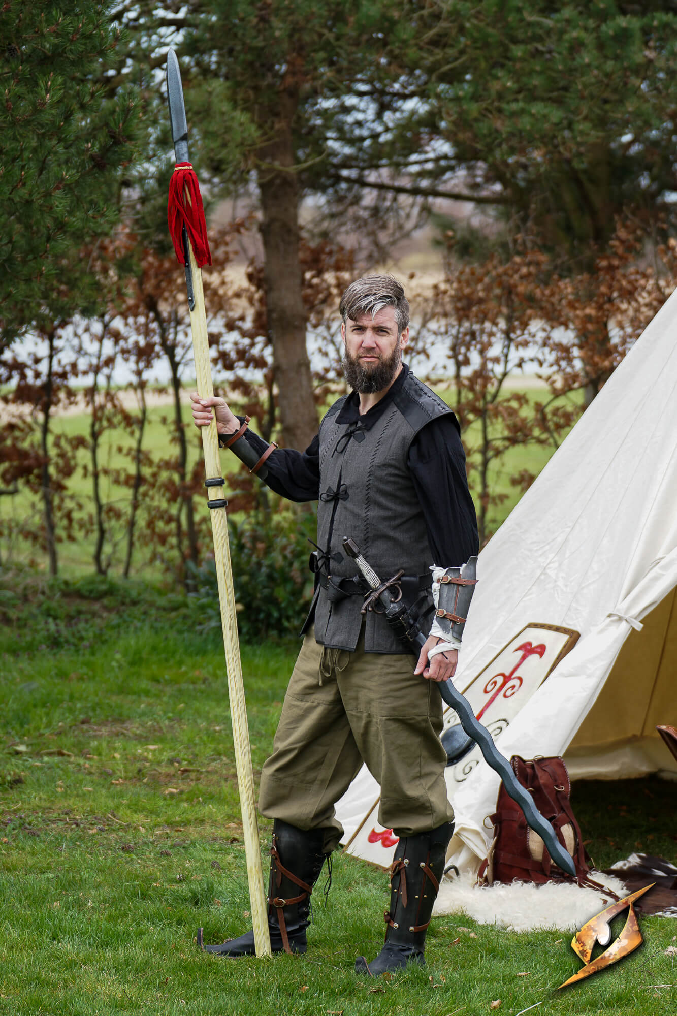 Person in historical attire holding a Landsknecht Pike at a campsite.