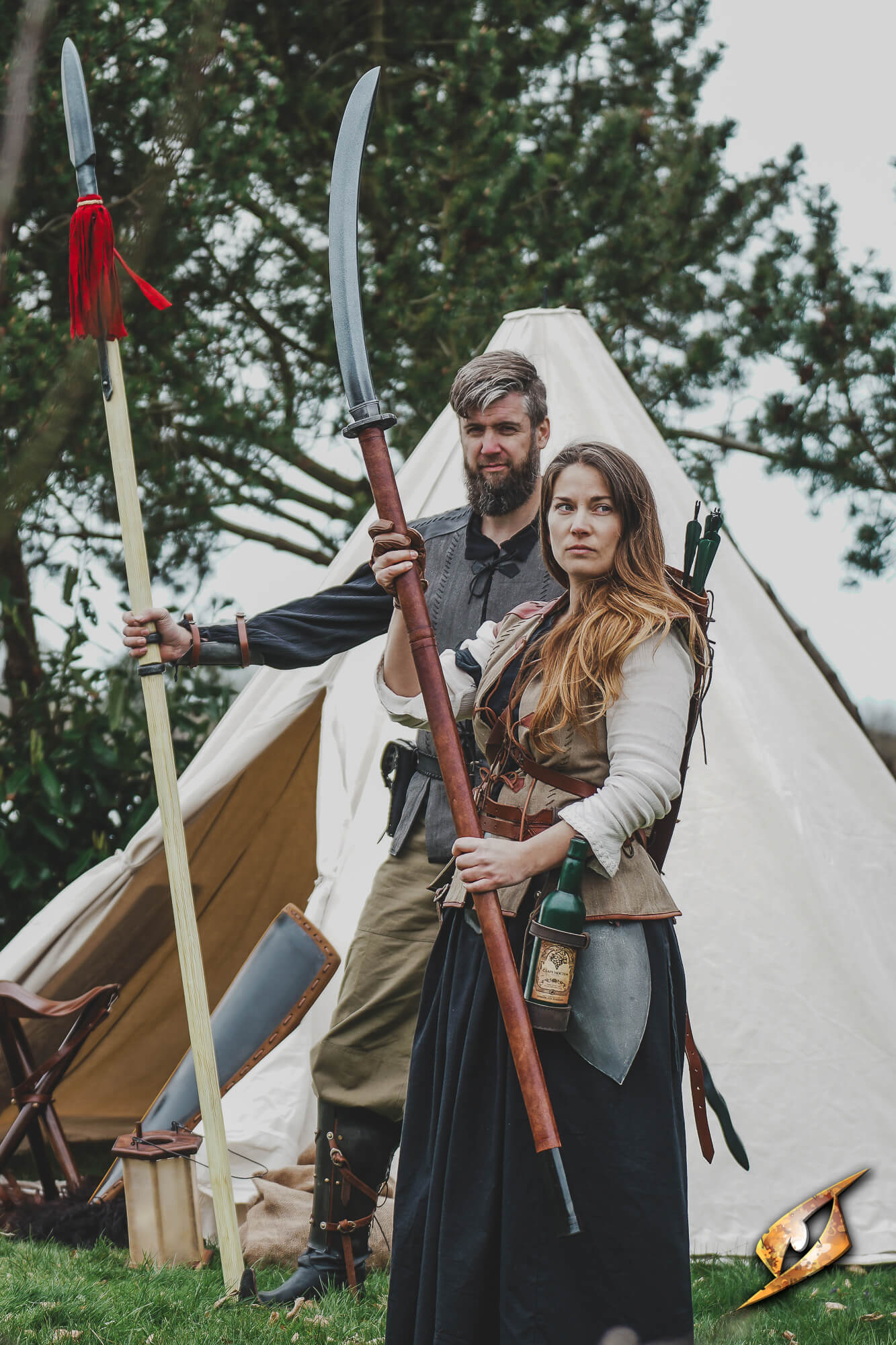 Naginata compact held by a woman, alongside a man with a spear, in a camp setting.