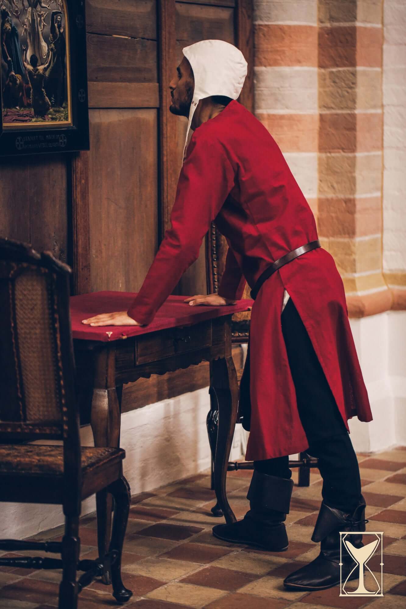 Man wearing a Medieval Riding Tunic in a historical setting, showcasing deep splits for mobility.