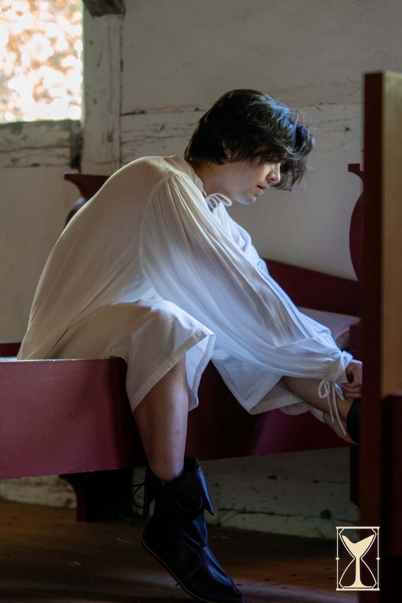 Person wearing a relaxed-fit Shirt Bartholomew seated, showcasing its classic design for historical reenactments.