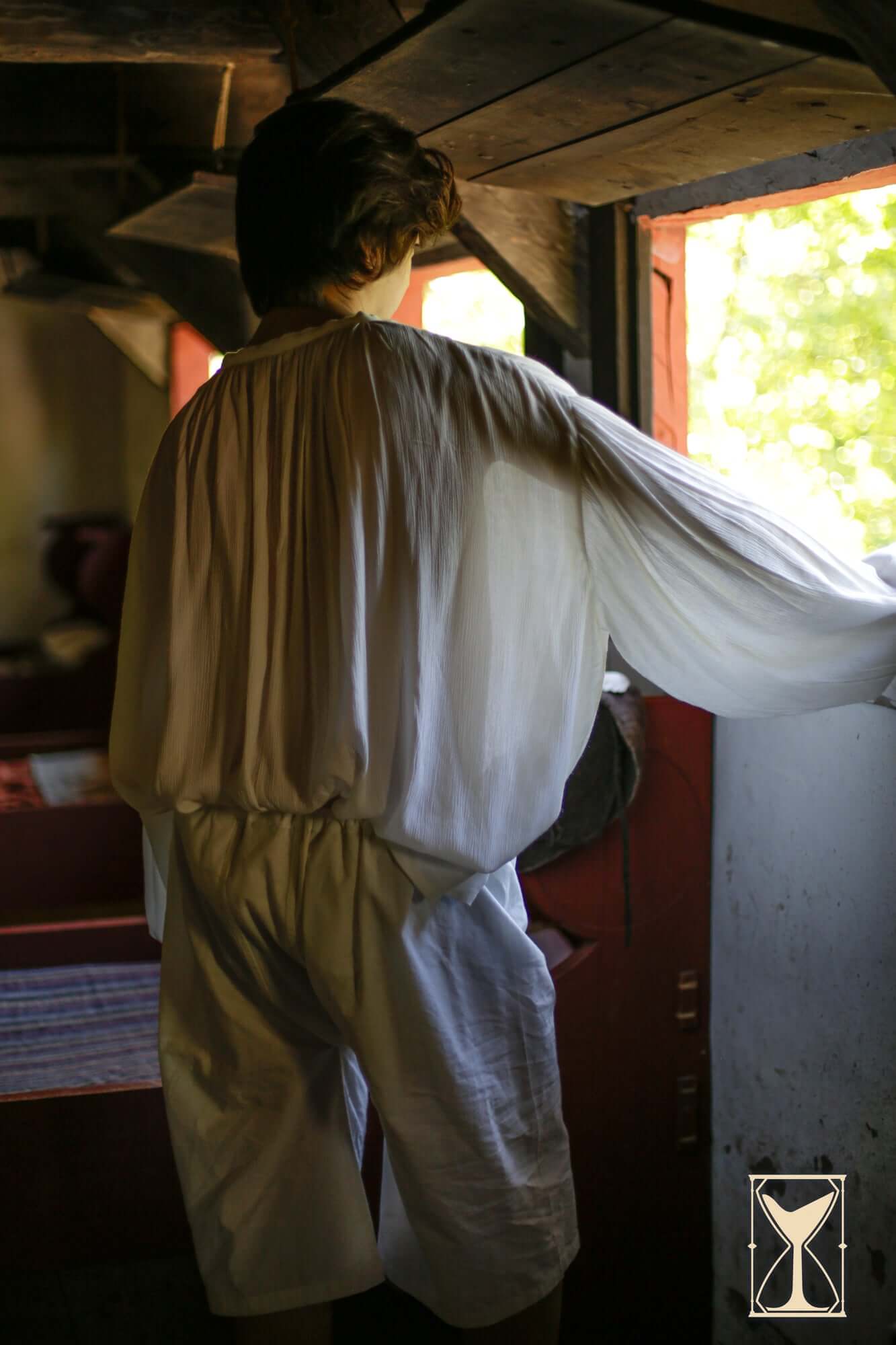 Person wearing Braies - Long looking out of a window, showcasing a historical medieval outfit.