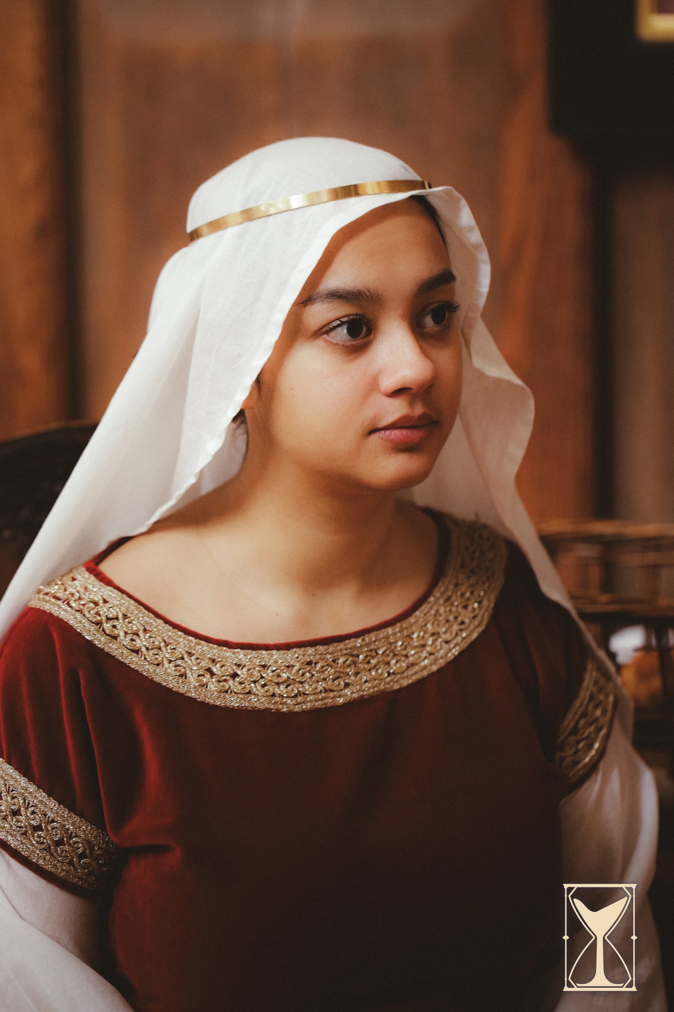 A woman wearing the Bliaut Noble dress, featuring velvet and muslin fabrics, with a historical medieval style.