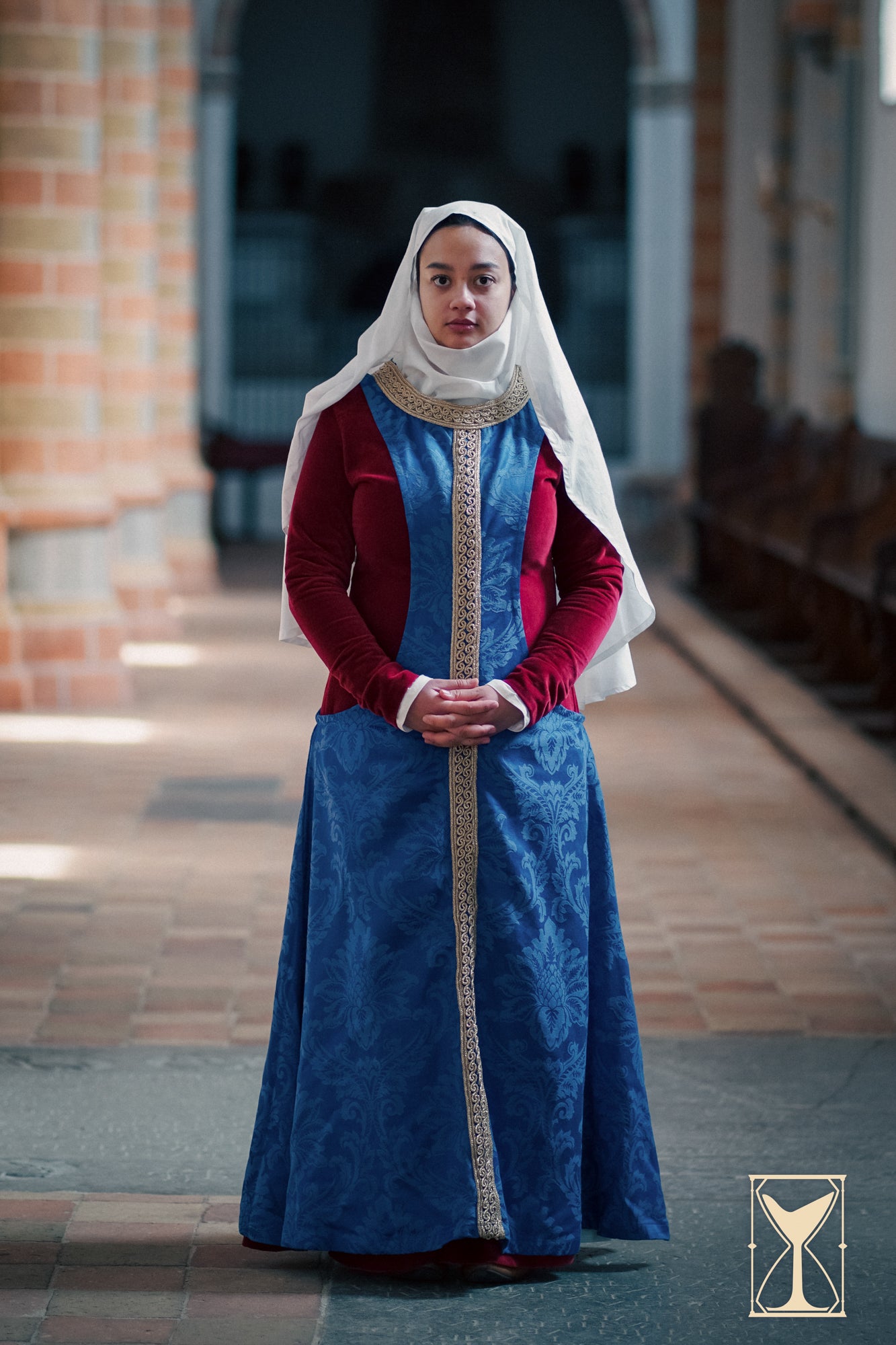 Pellote - Medieval Dress, a sleeveless surcoat in blue brocade, worn with a white veil and red sleeves, styled in a historical setting.
