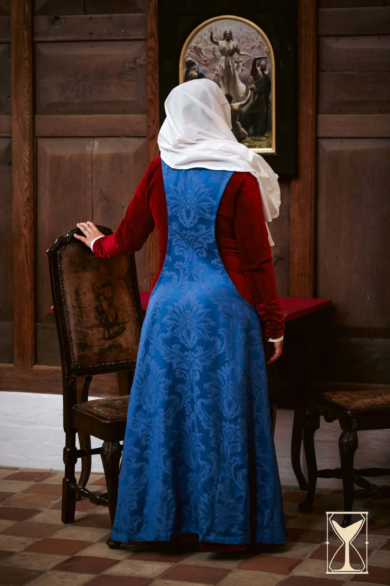 Back view of a woman wearing the Pellote - Medieval Dress, showcasing its elegant design and patterned fabric.
