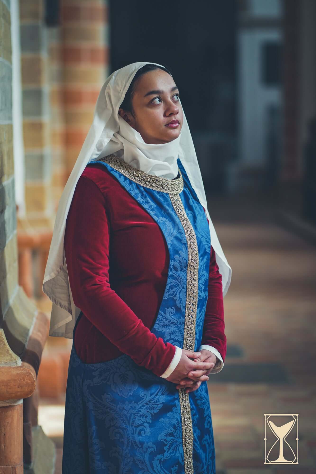 Pellote - Medieval Dress worn by a woman in a historic setting, showcasing elegant sleeves and intricate design.
