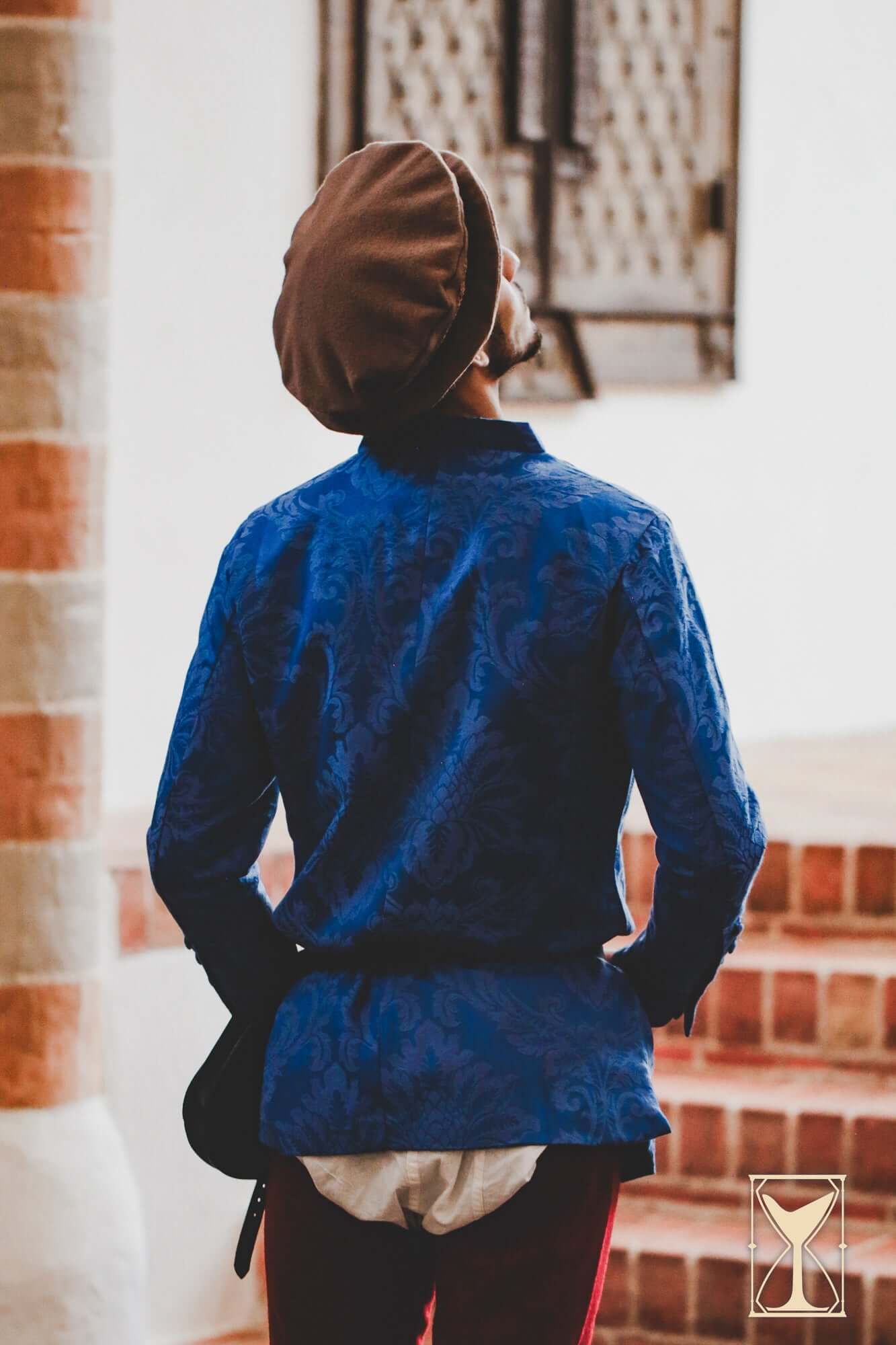 Person wearing a Flat Hat Edward, showcasing a historical Renaissance outfit with a blue patterned shirt.