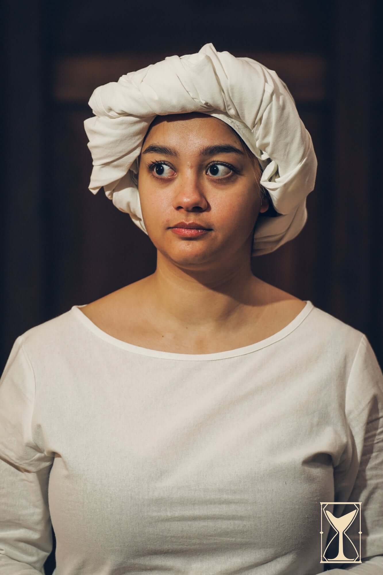 A woman wearing a rectangular veil and fillet made of cotton, showcasing historical costume attire.