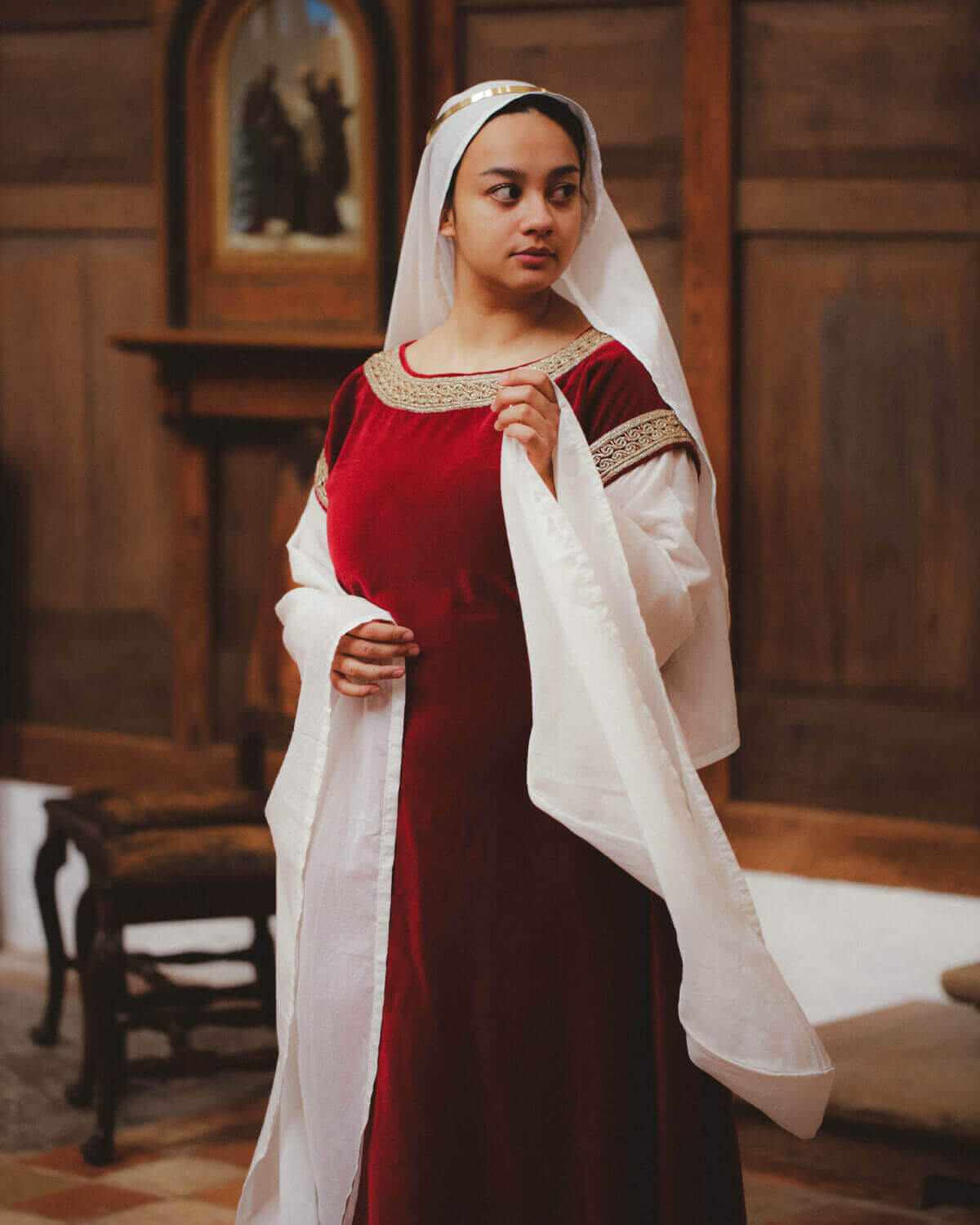 Woman in red velvet and white medieval dress, showcasing historical reenactment fashion.