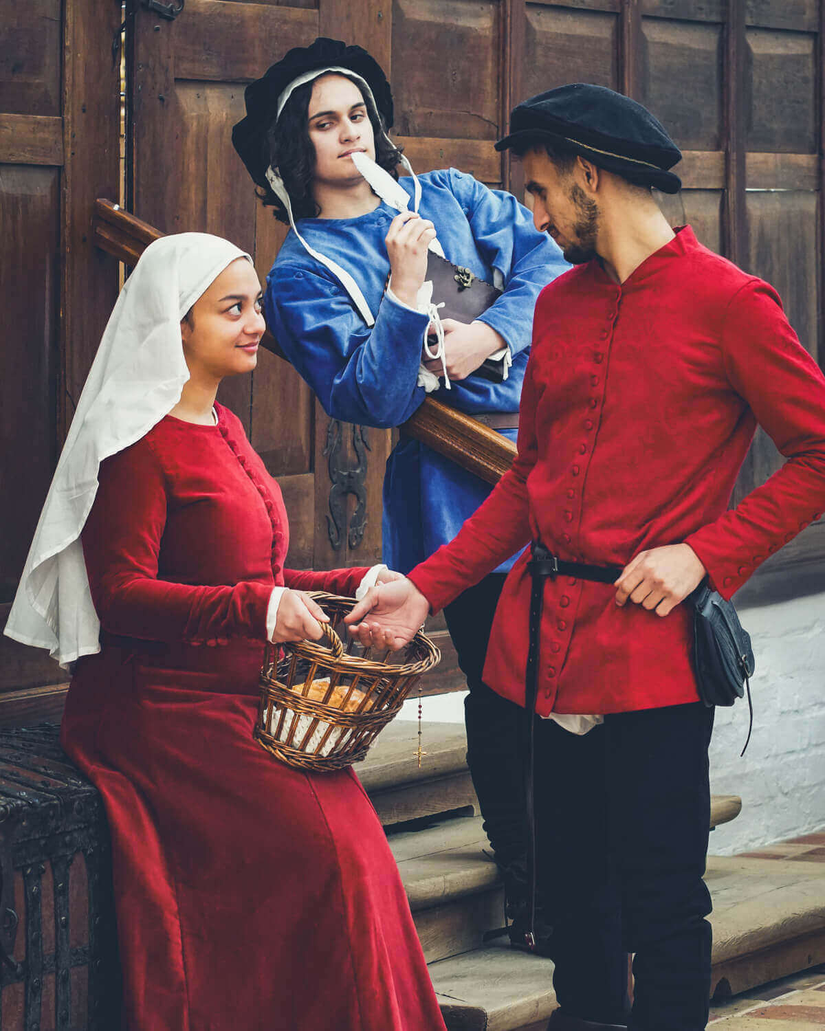 Woman in red dress with basket, man in red jacket, and man in blue shirt.