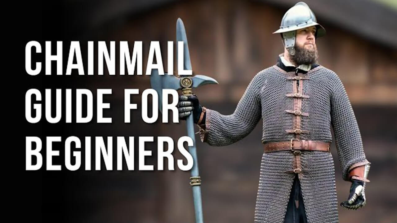 A person dressed in medieval chainmail armor stands holding a large chainmail spear, with large white text on the left reading 'CHAINMAIL GUIDE FOR BEGINNERS' against a blurred outdoor background.