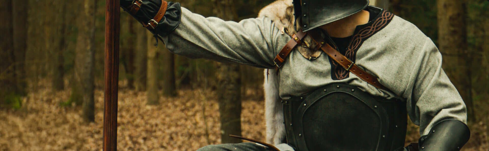Person in medieval armor holding a spear in a forest setting